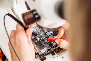 Young woman repairing computer hardware in service center. Repairing and fixing service in lab. Electronics repair service concept.